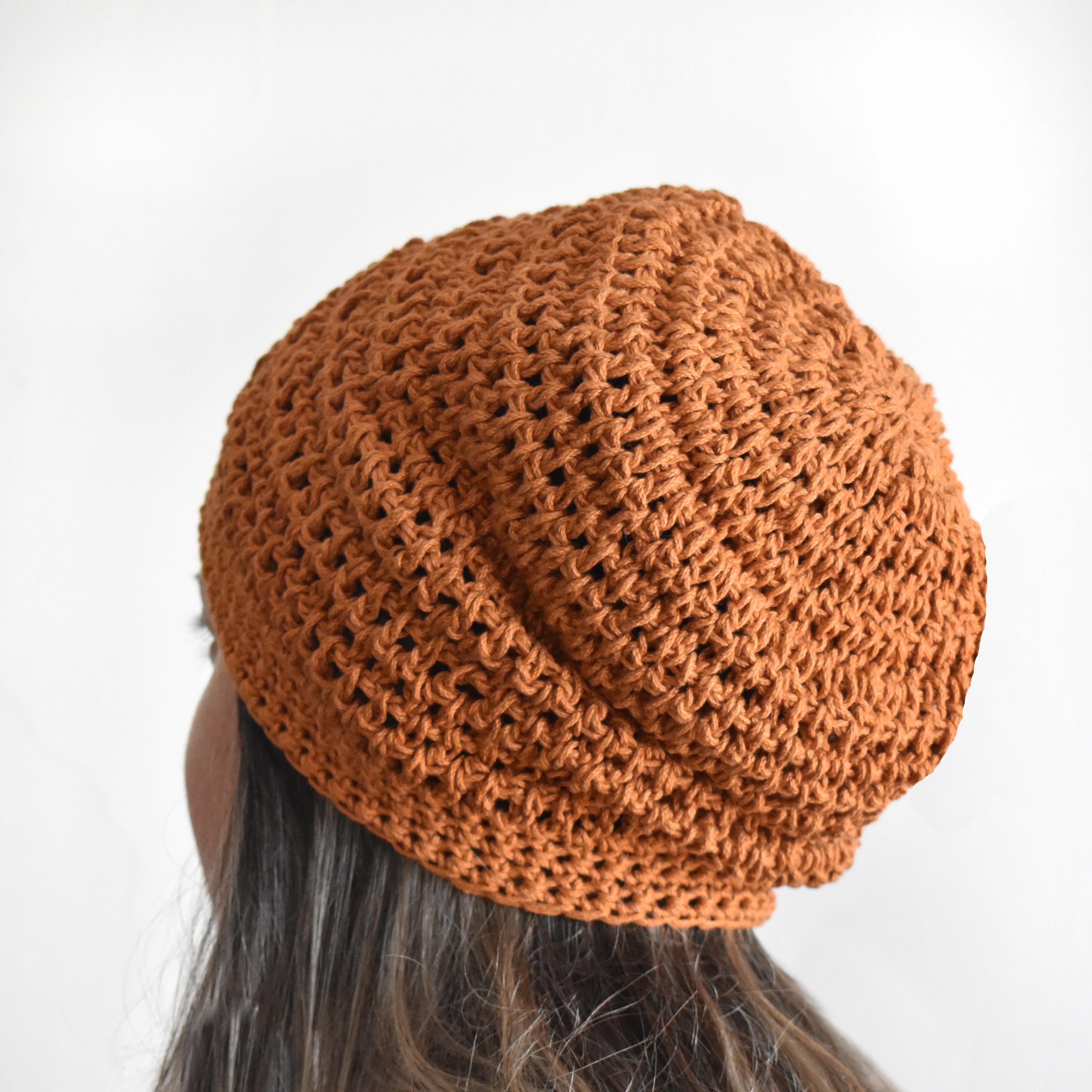 Orange knitted beanie on a person against a white background.