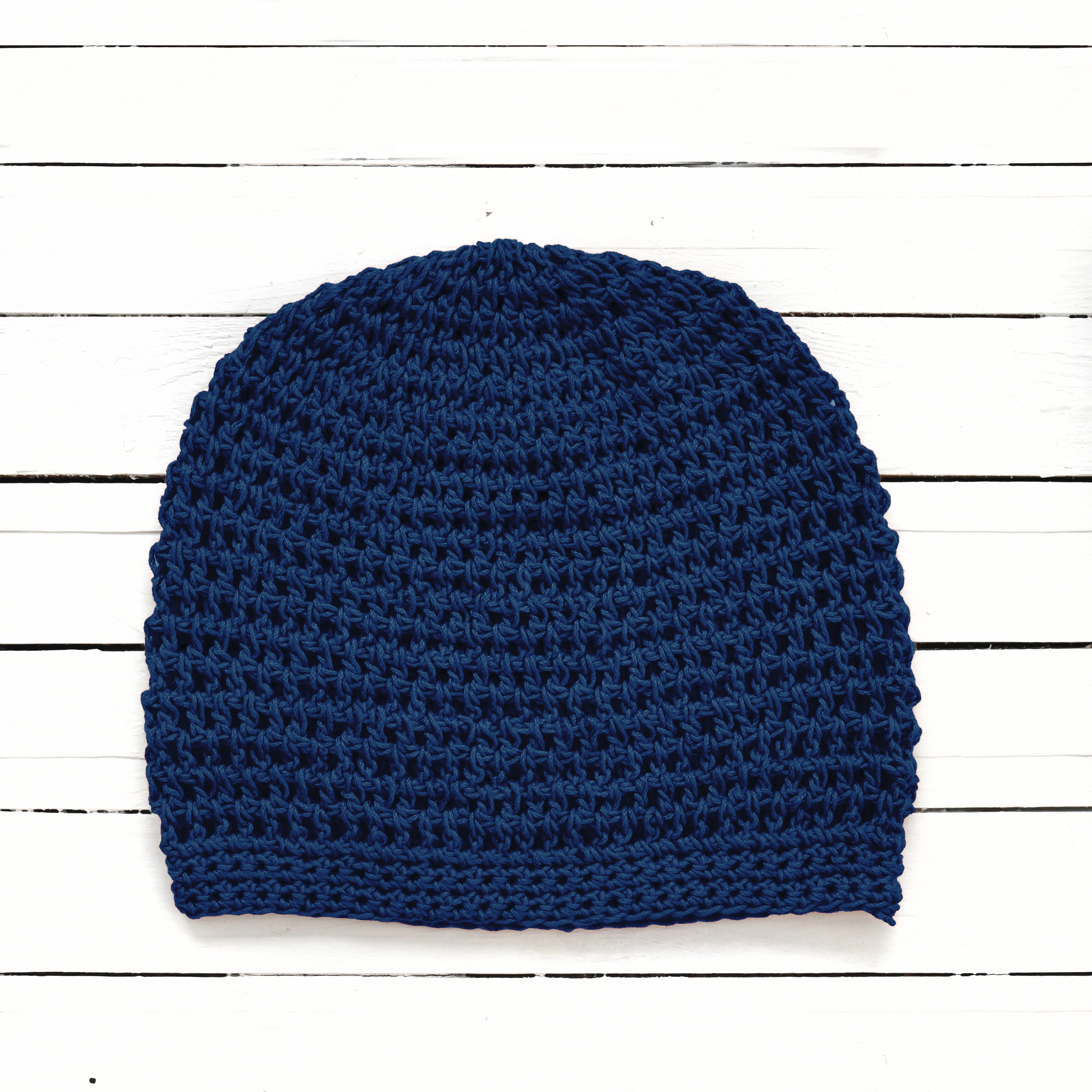 Navy blue knitted beanie on a white wooden surface.