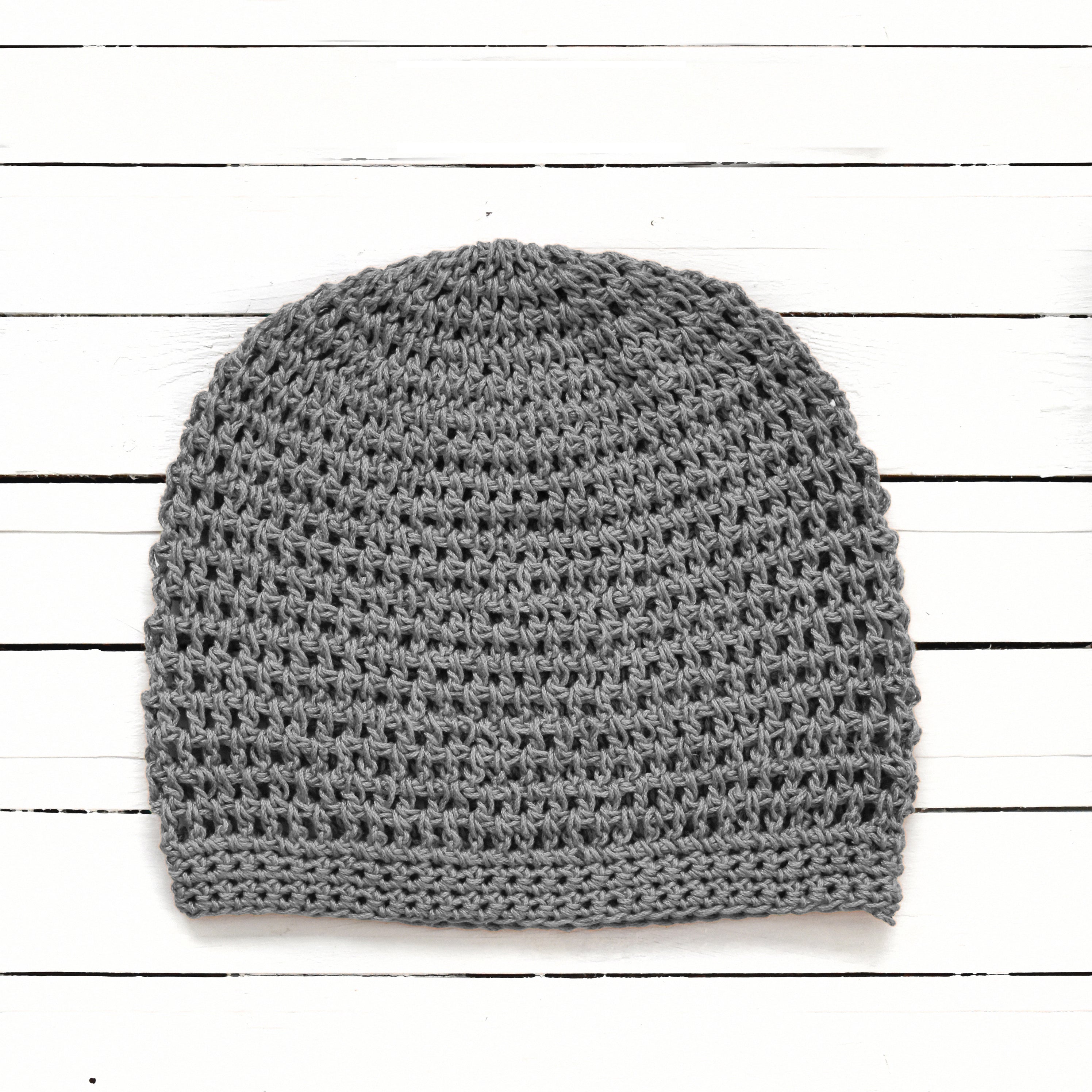 Gray crochet beanie on a white wooden surface.