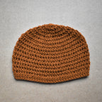 Amber brown knitted beanie on a neutral kraft background.