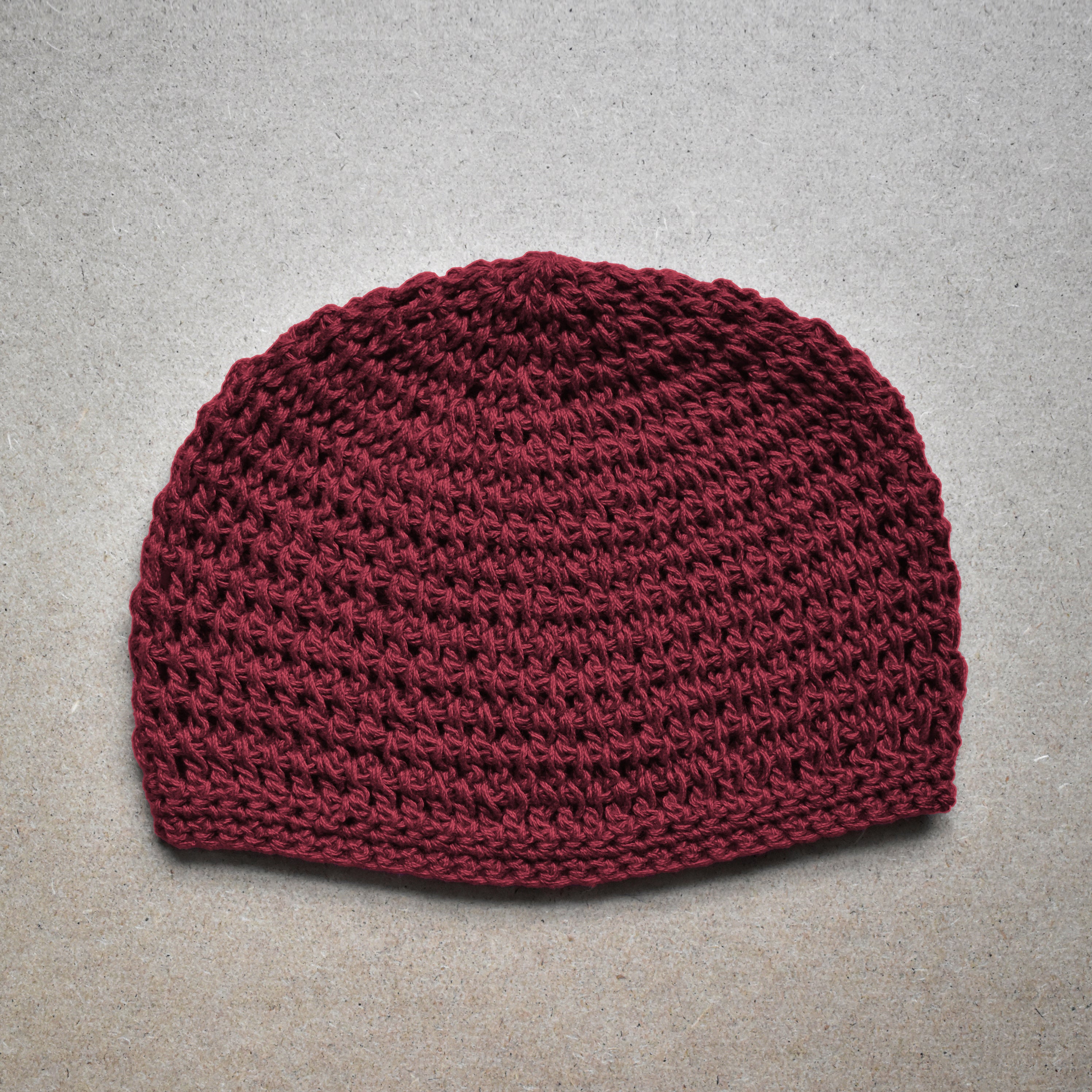 Maroon knitted beanie on a gray background.