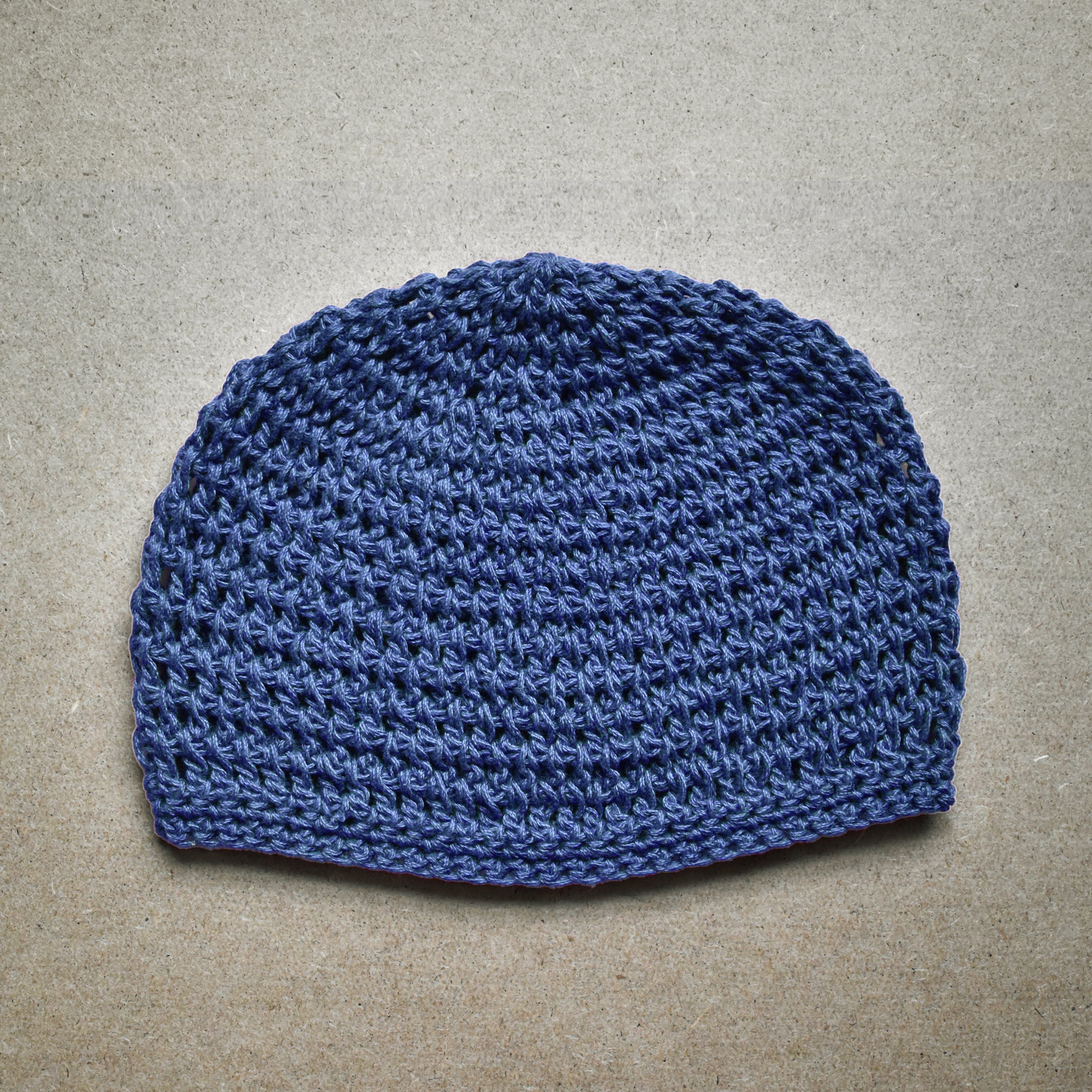 Blue knitted beanie on a beige background.