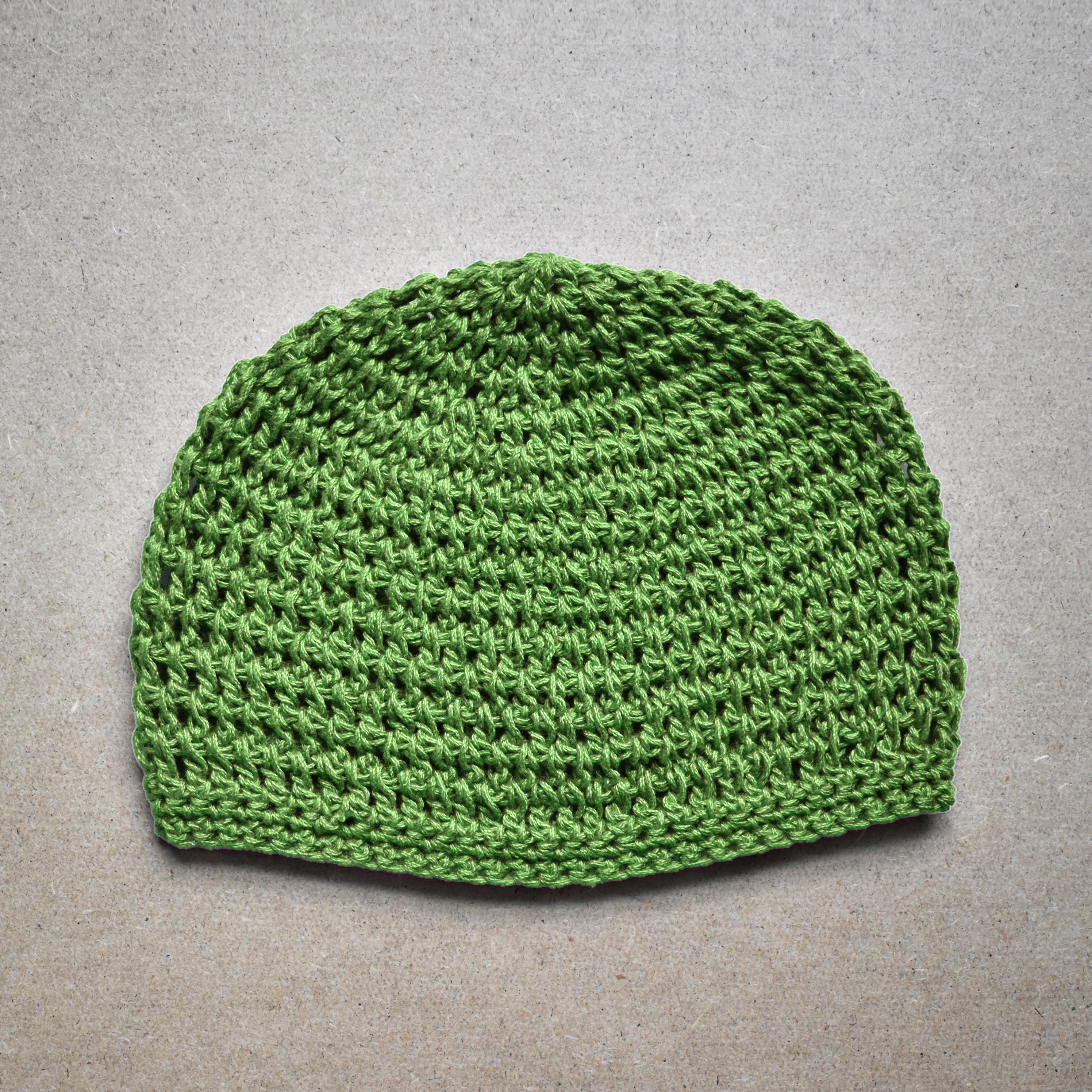 Bright green knitted beanie on a gray background.