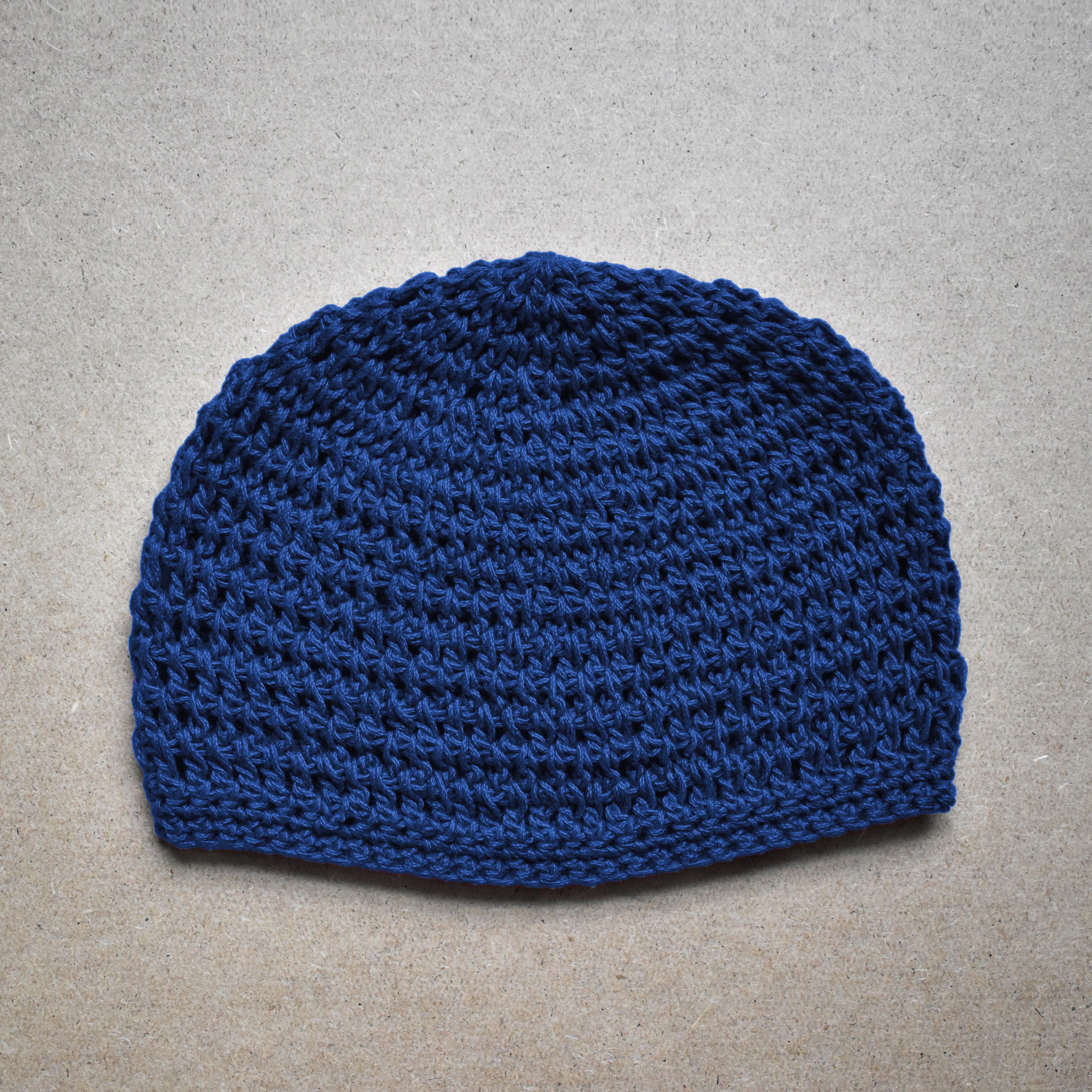 Blue knitted beanie on a gray background.