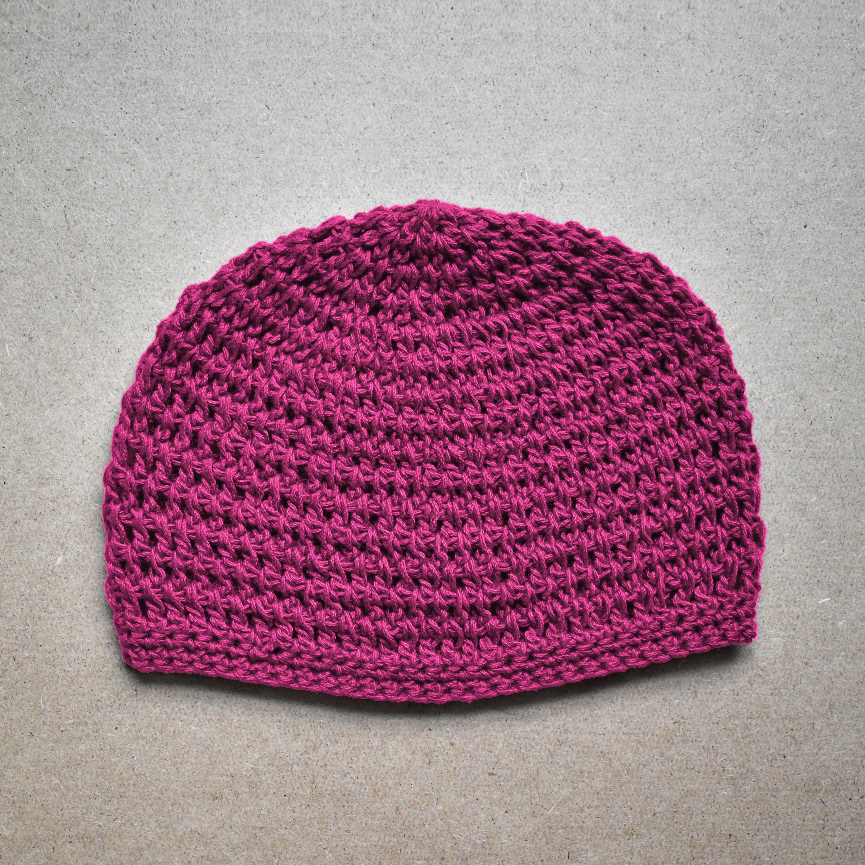 Bright pink knitted beanie on a gray background.