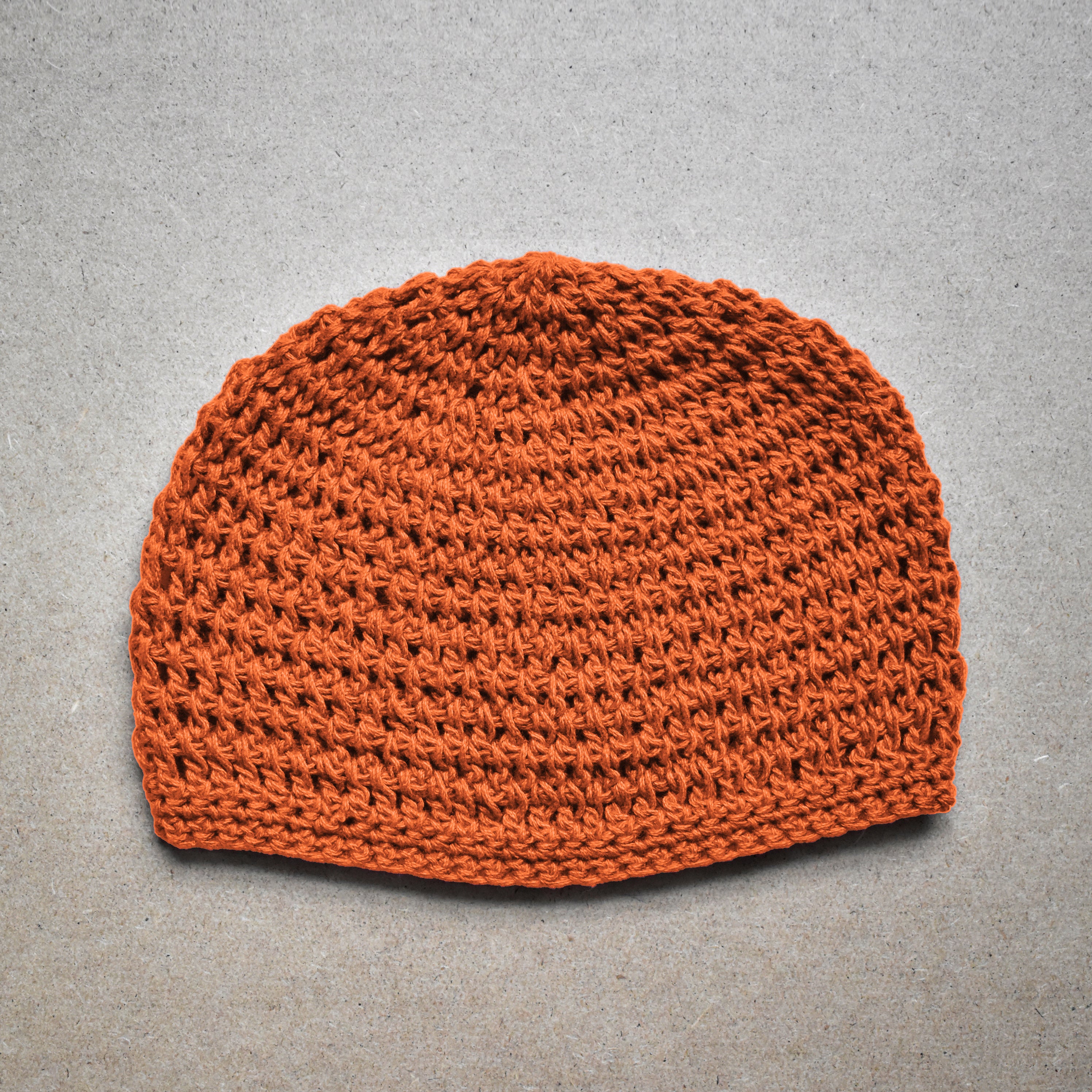Orange knitted beanie on a kraft background.