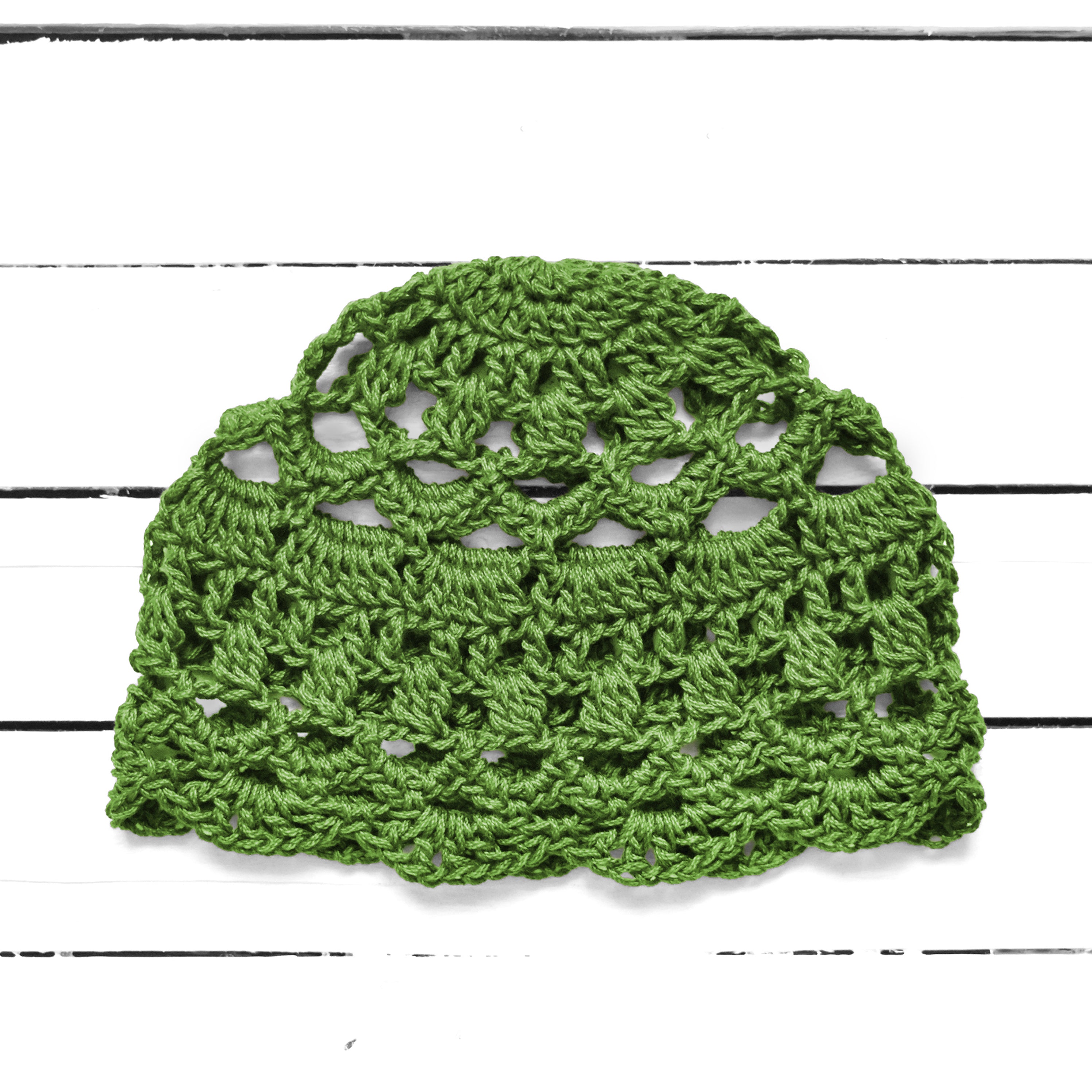 Bright green lace crocheted summer cap on a white background.