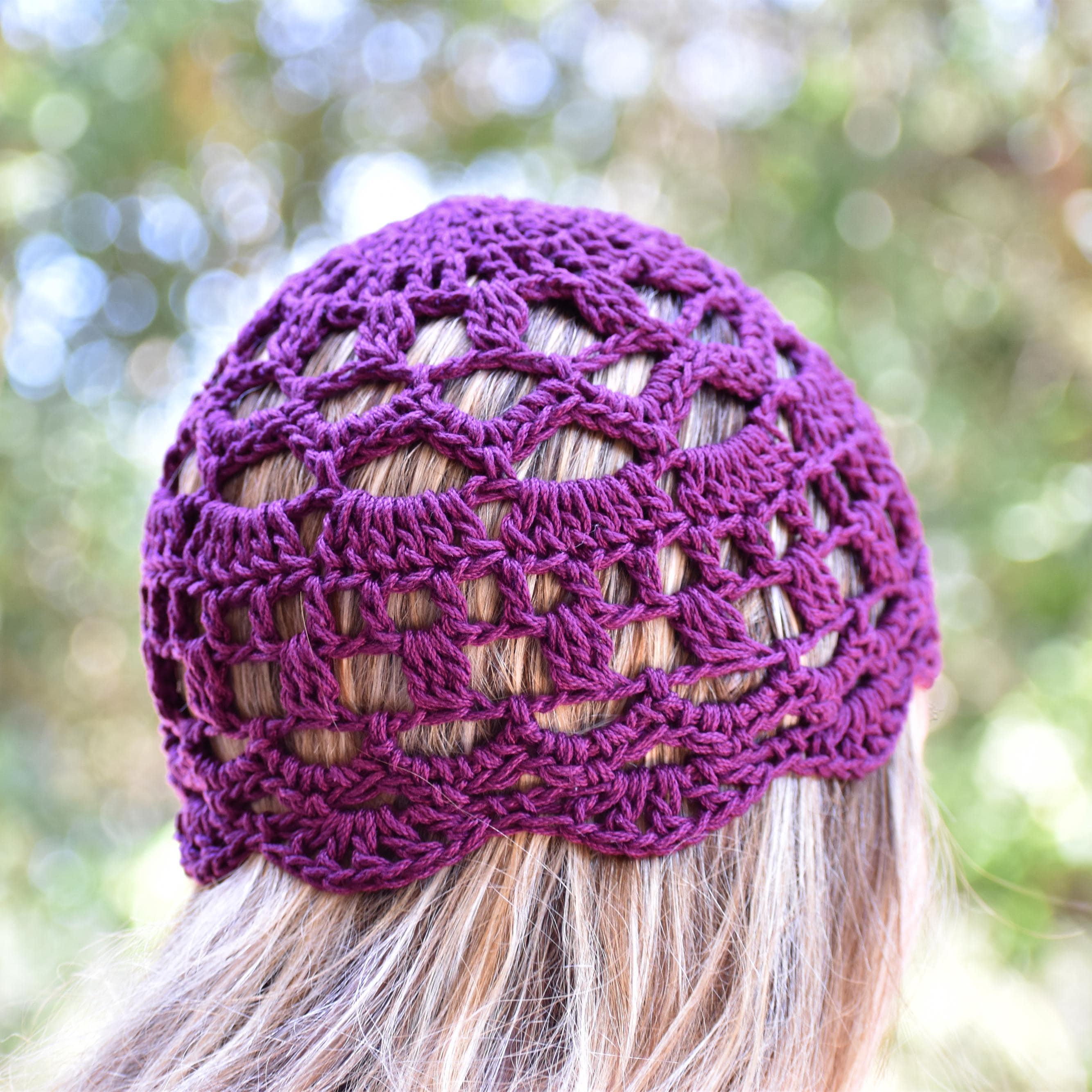 Purple crocheted lace skull cap worn by a person looking at a blurred natural outdoor background.