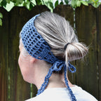 Person wearing a blue knitted headband, standing against a wooden fence.