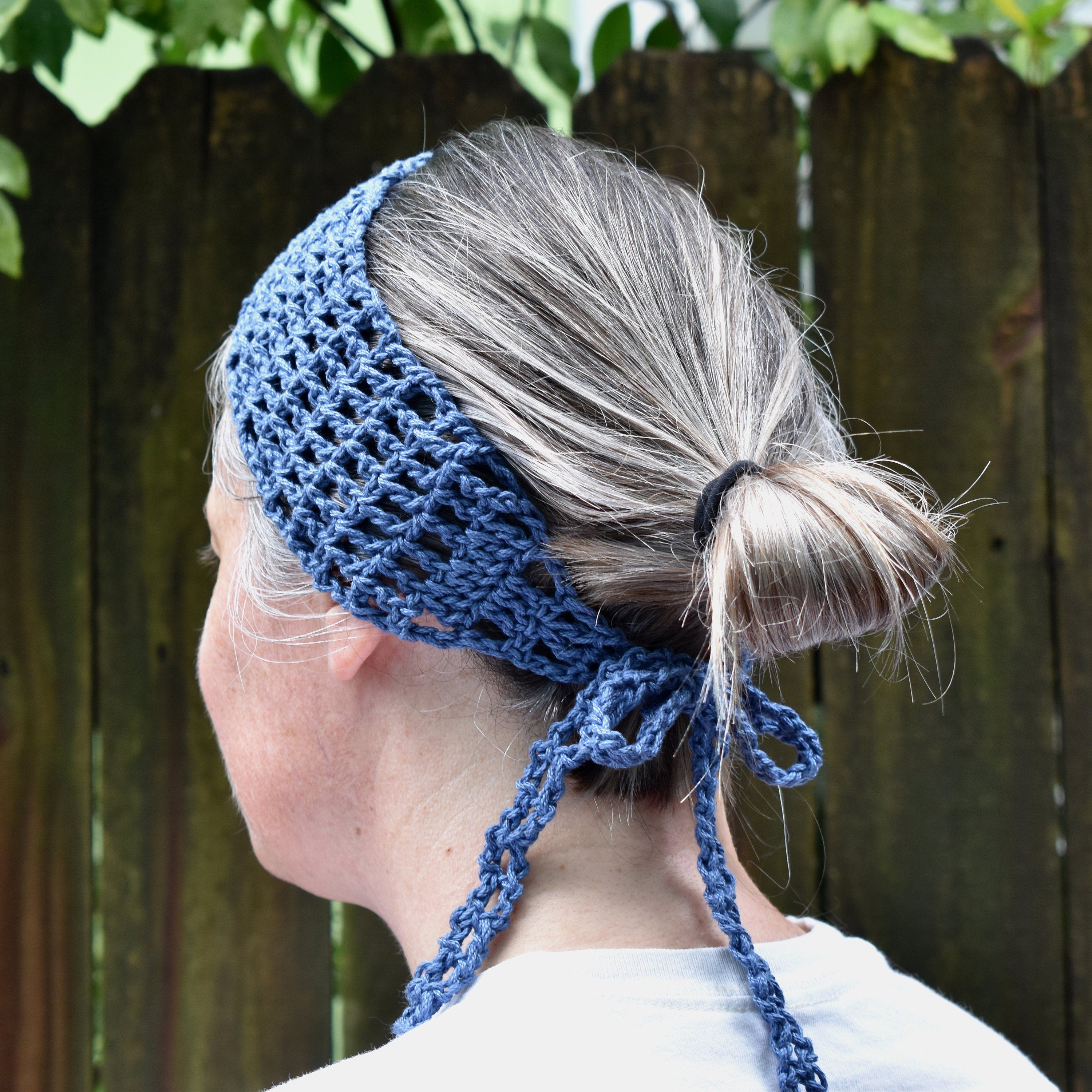 Person wearing a blue knitted headband, standing against a wooden fence.