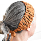 Person wearing an orange knitted headband with a white background.