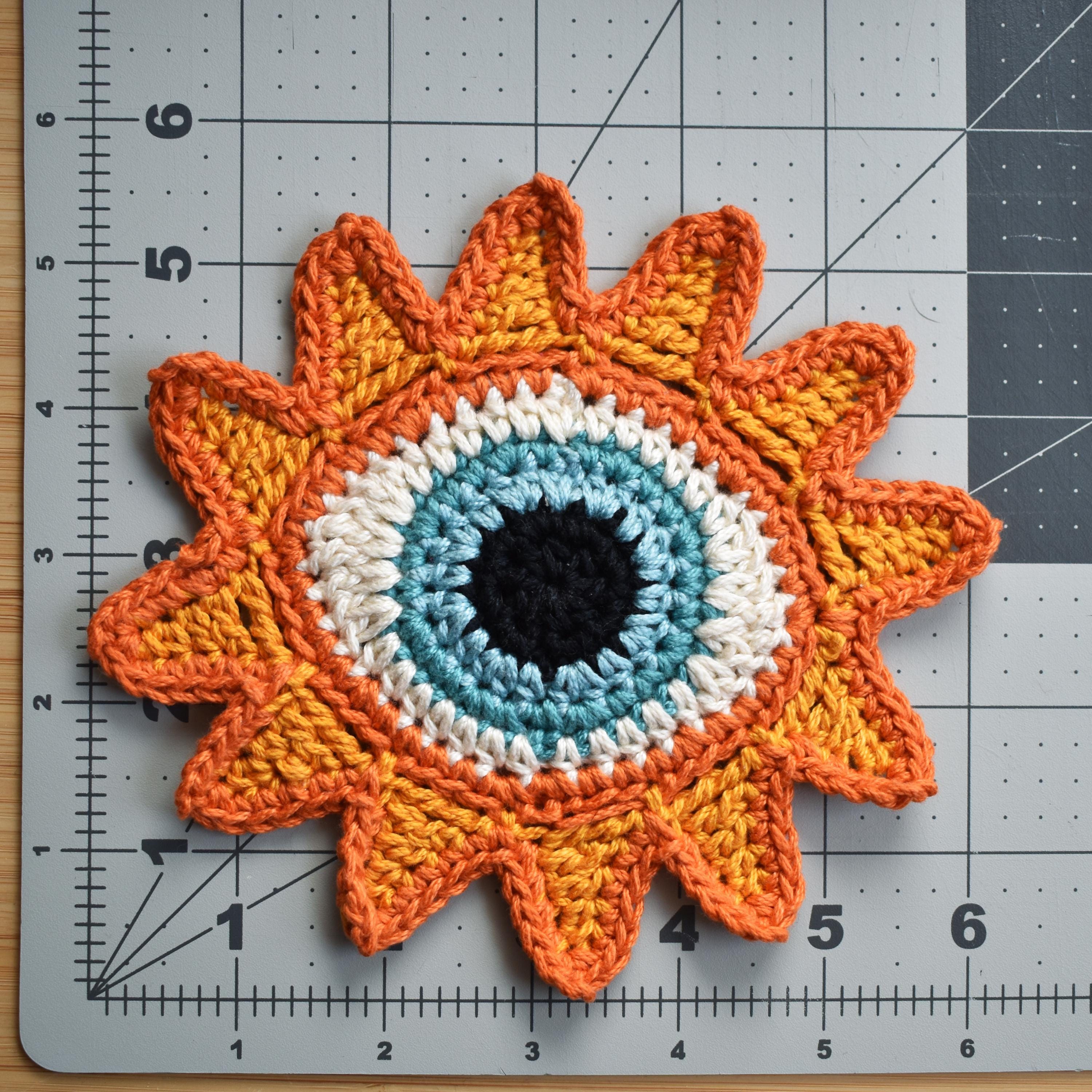 Crocheted sunflower patch on a cutting mat with measurements.