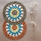 Two crocheted coasters with a floral pattern on a natural kraft background, accompanied by a dried sprig of flowers.