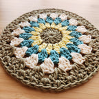 Crocheted round mat with multicolor pattern on a wooden surface.