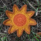Crocheted sunshine patch on a grassy background.