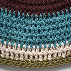 Close-up of a crocheted hat with a multicolored striped pattern on a white background.