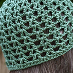 Close-up of a green knitted skull cap on a person's head.