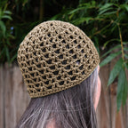 Person wearing a beige crochet hat with a blurred natural background.