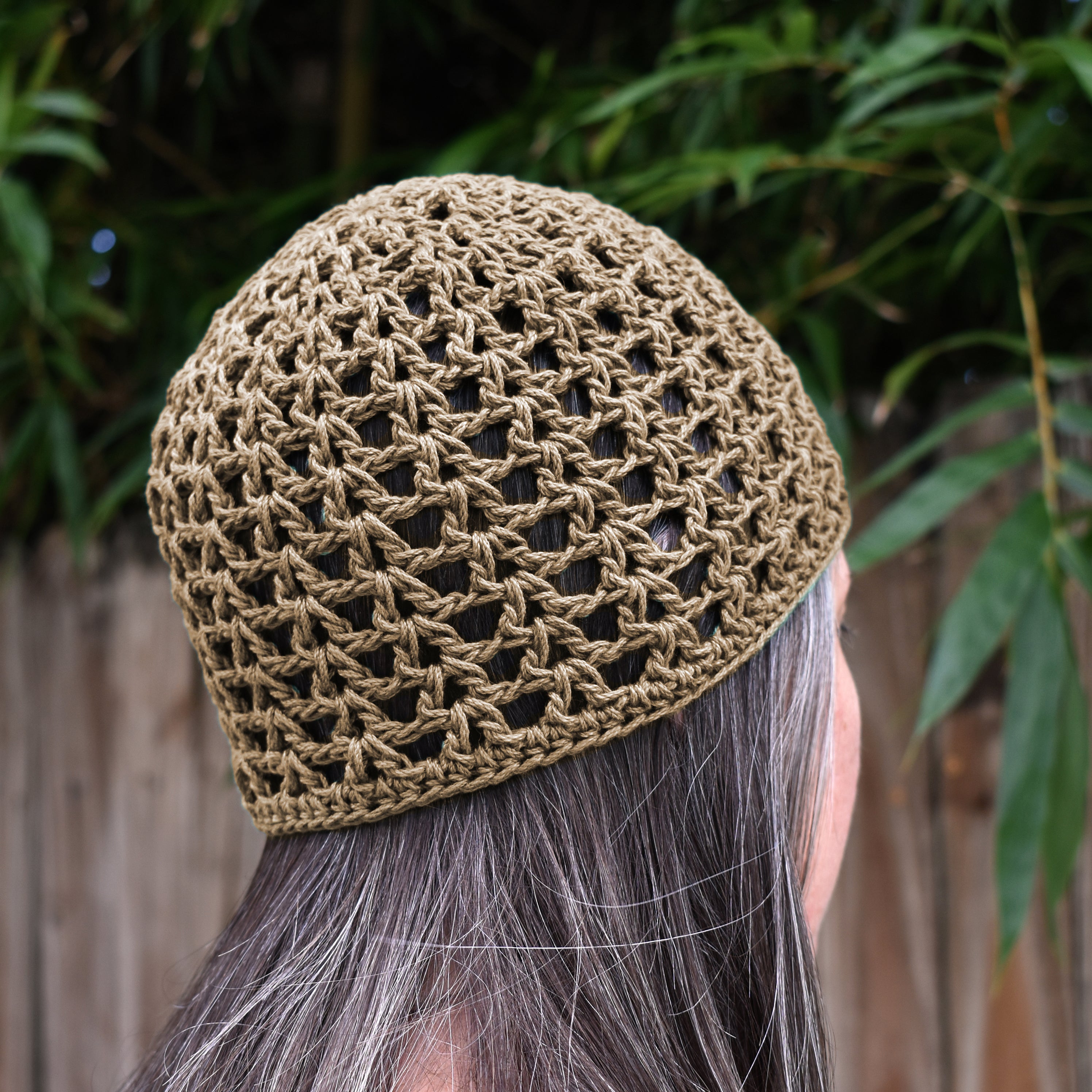 Person wearing a beige crochet hat with a blurred natural background.